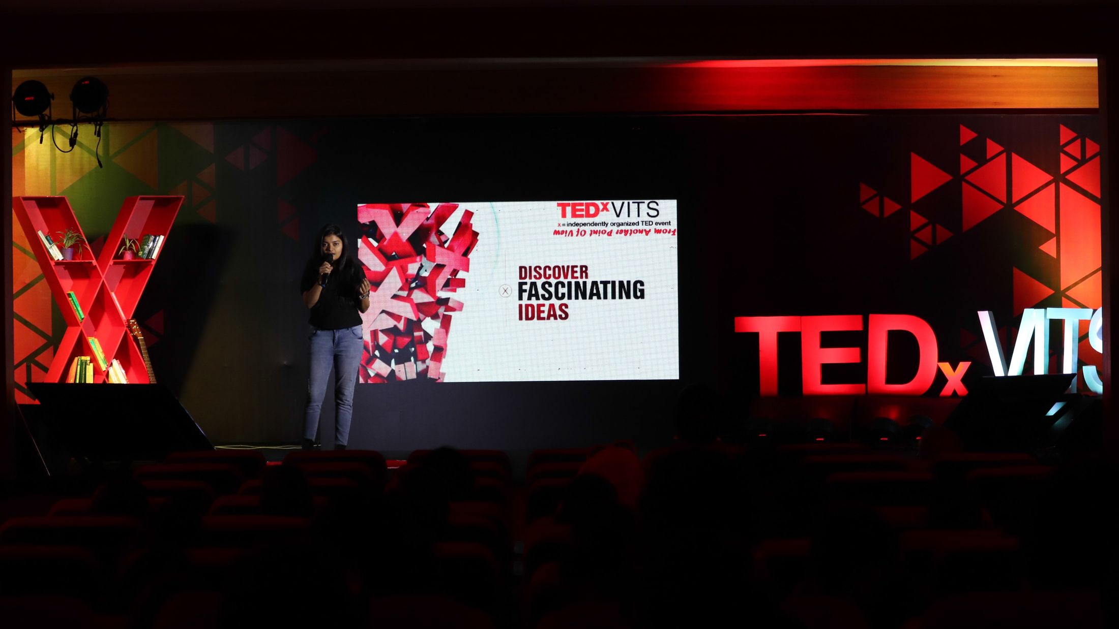 The TEDxVITS stage, glowing red, with a speaker beneath a giant X